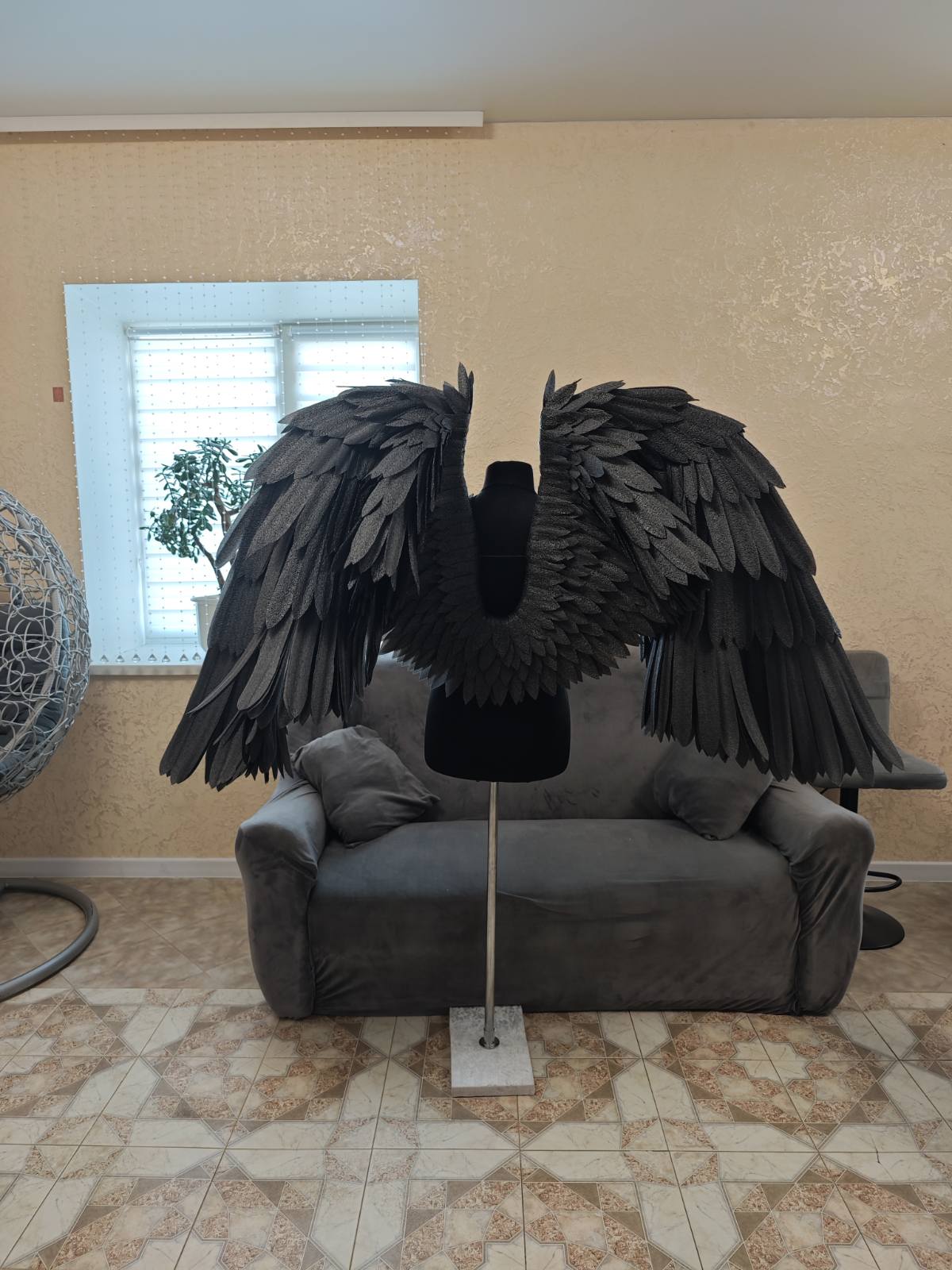 Black angel wings on a stand in a living room setting