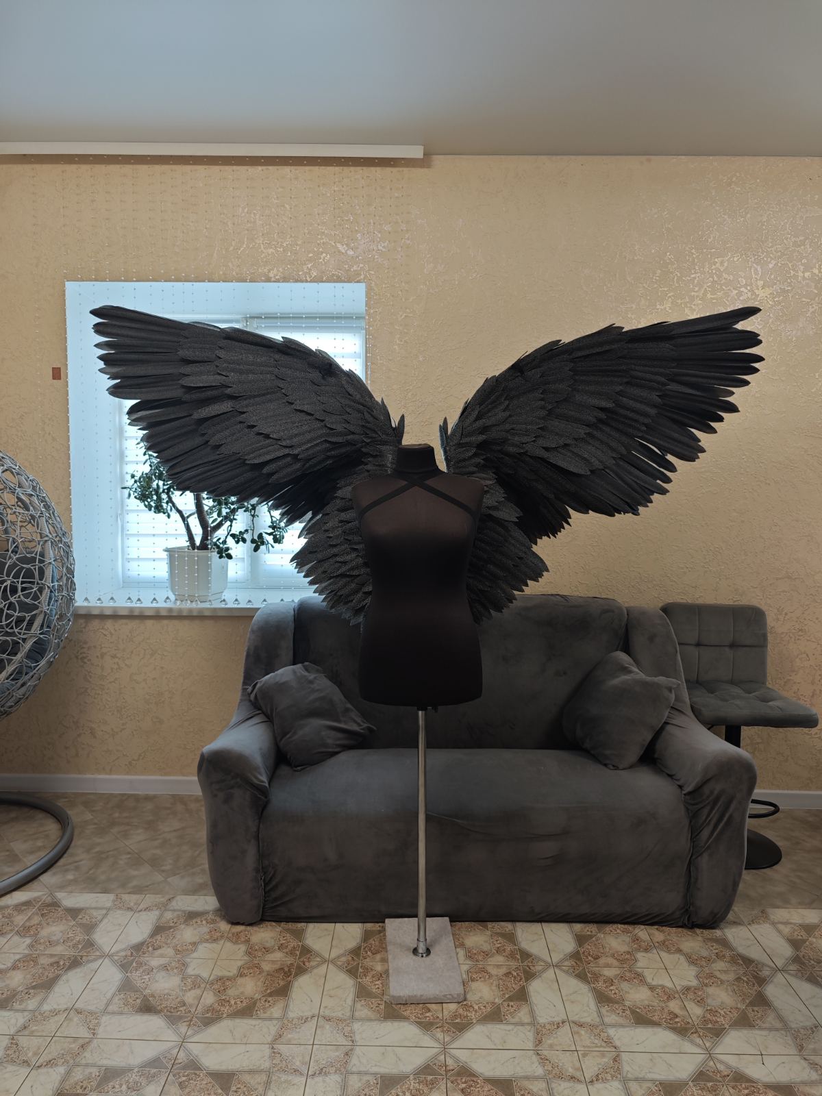Black feathered wings on a stand in a living room setting