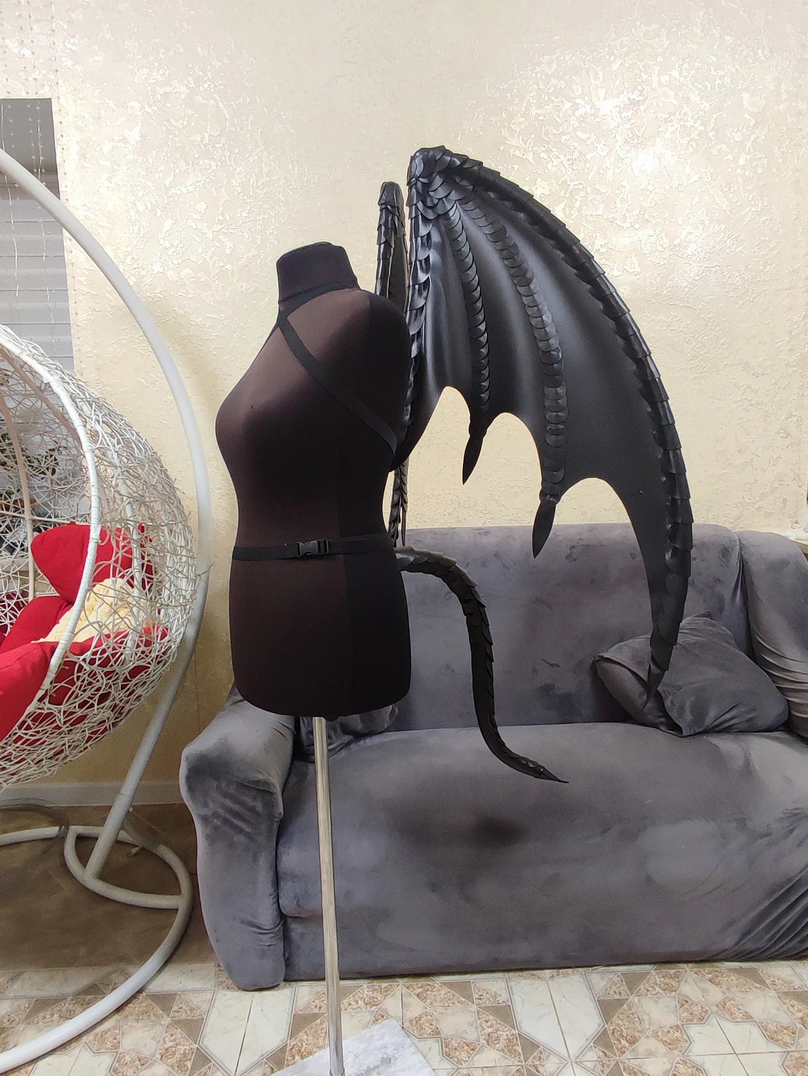 Mannequin with dragon wings on a couch in a living room setting