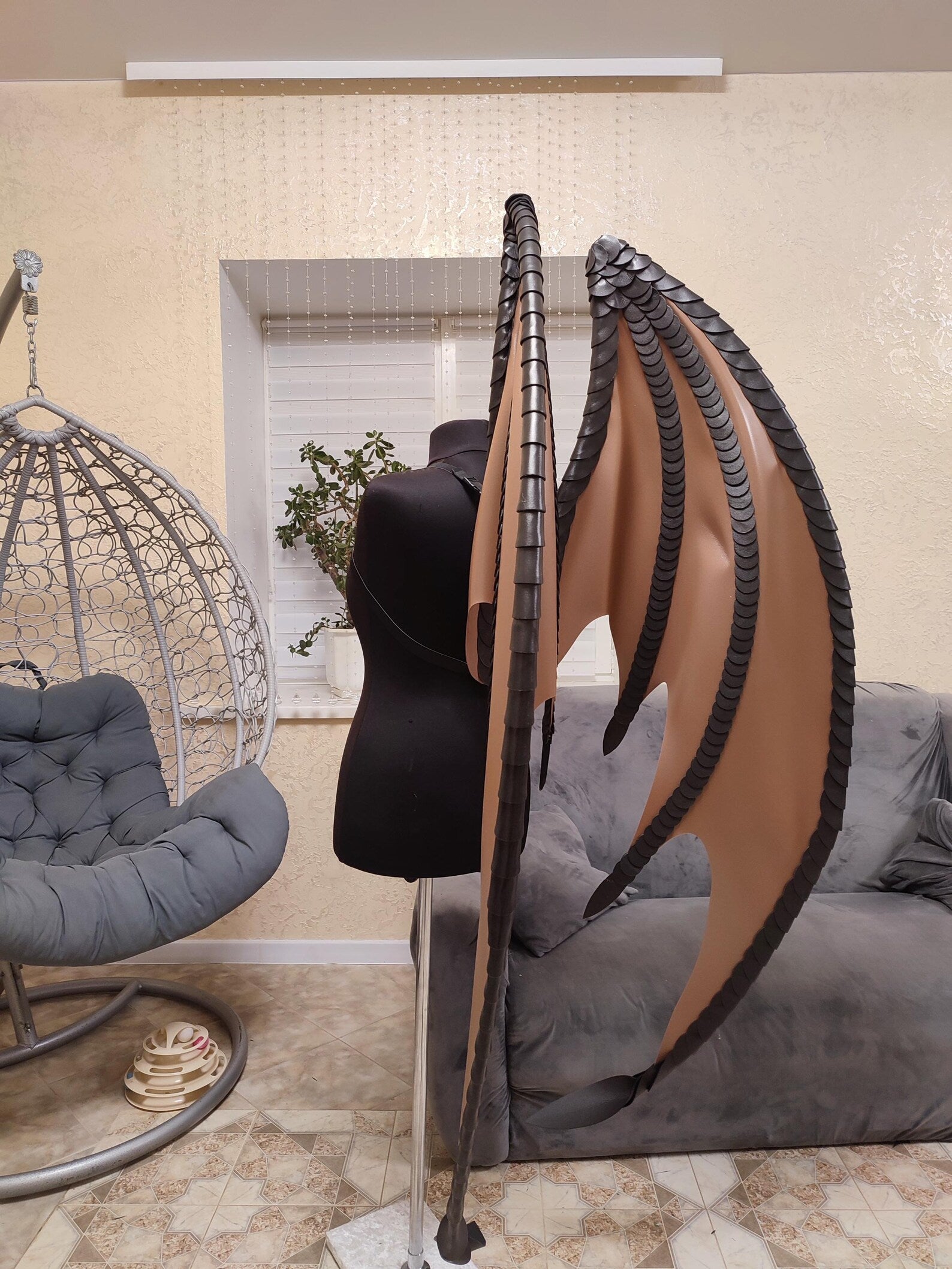 Brown dragon wings in modern living room with a hanging chair, gray sofa, and decorative plant.