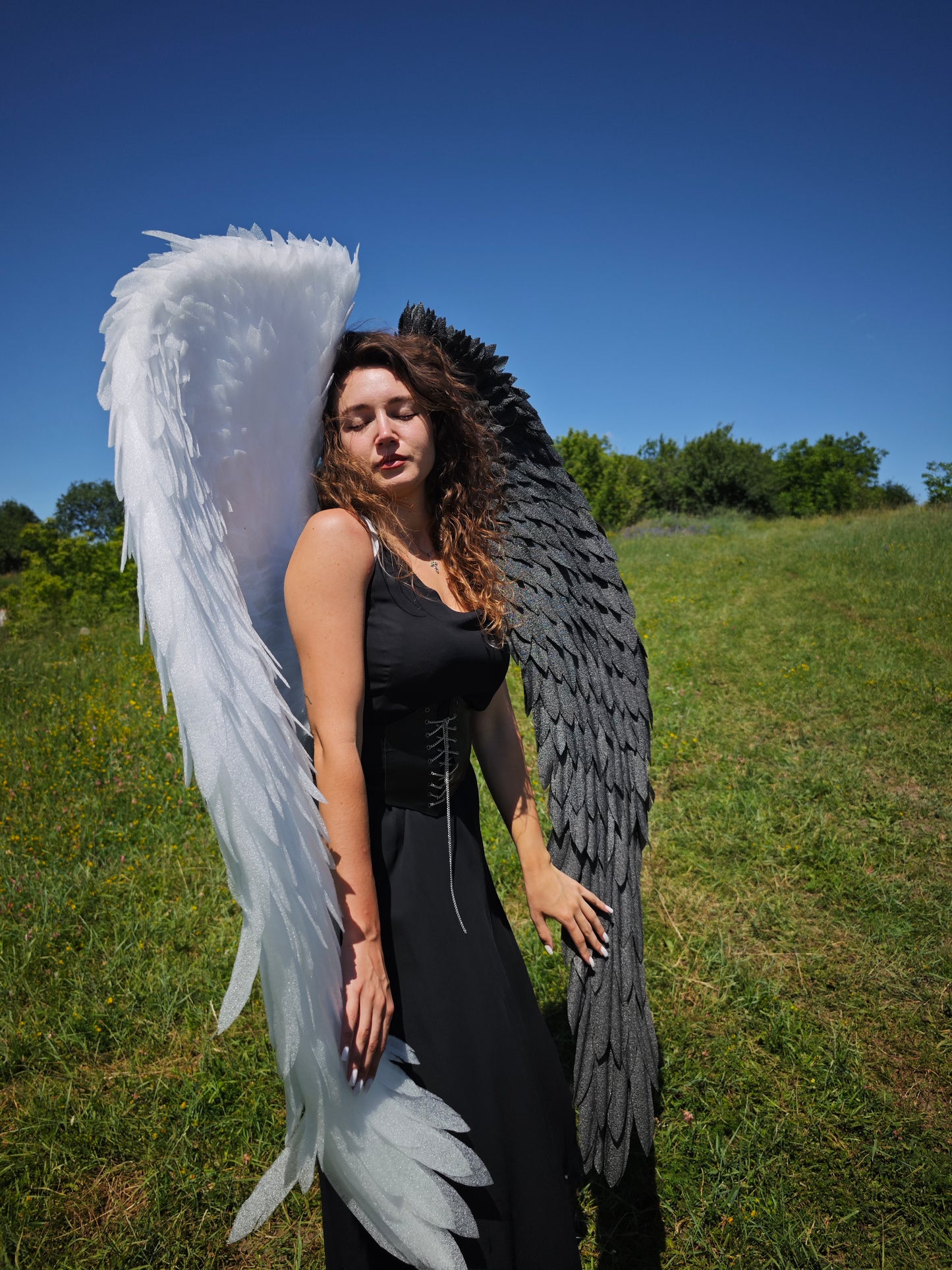 Person wearing large angel wings outdoors on a sunny day