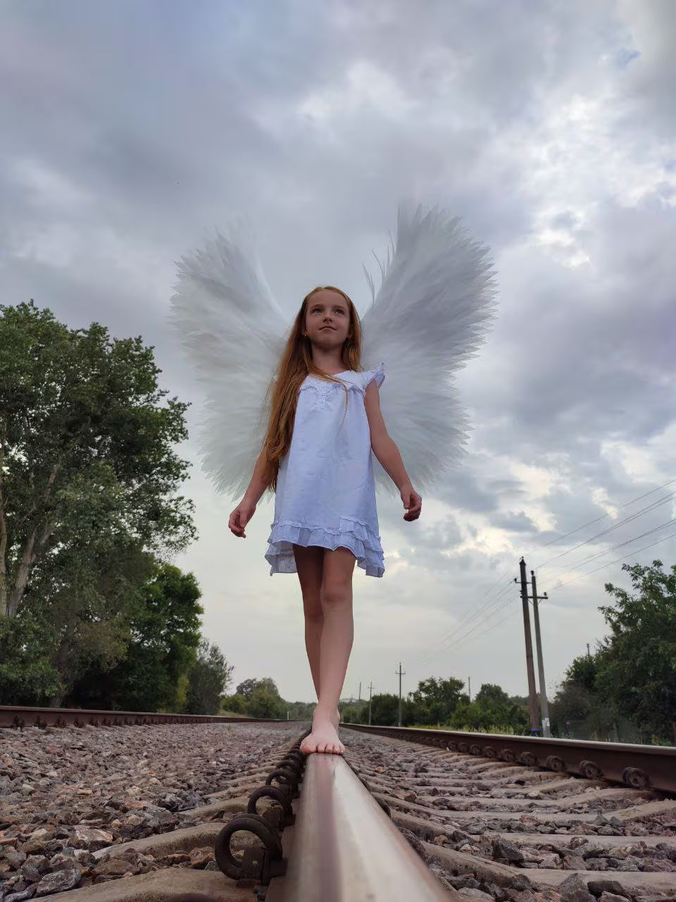 Handmade white angel wings with individually hand-cut foam feathers and adjustable shoulder straps for adults and children.